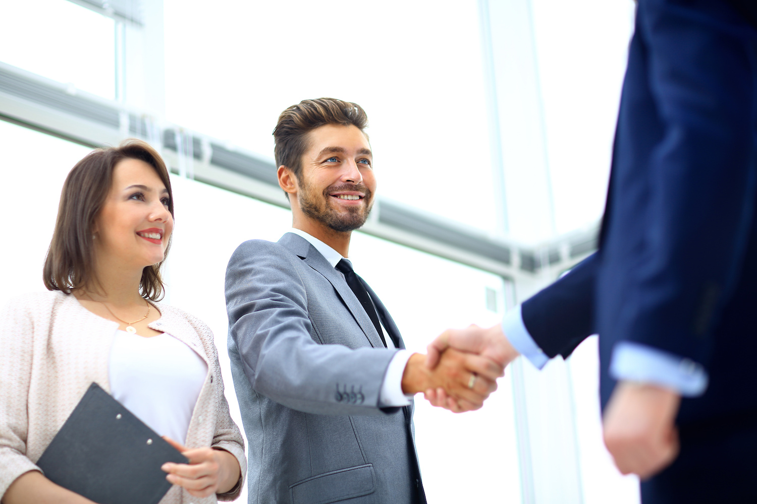 Business colleagues sitting at a table during a meeting with two Business colleagues during a meeting with two male executives shaking hands